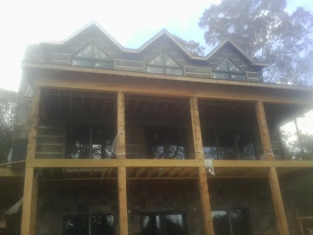Dormers and porch framing on a large log home under construction — Roof Coating work by our crew in De Soto