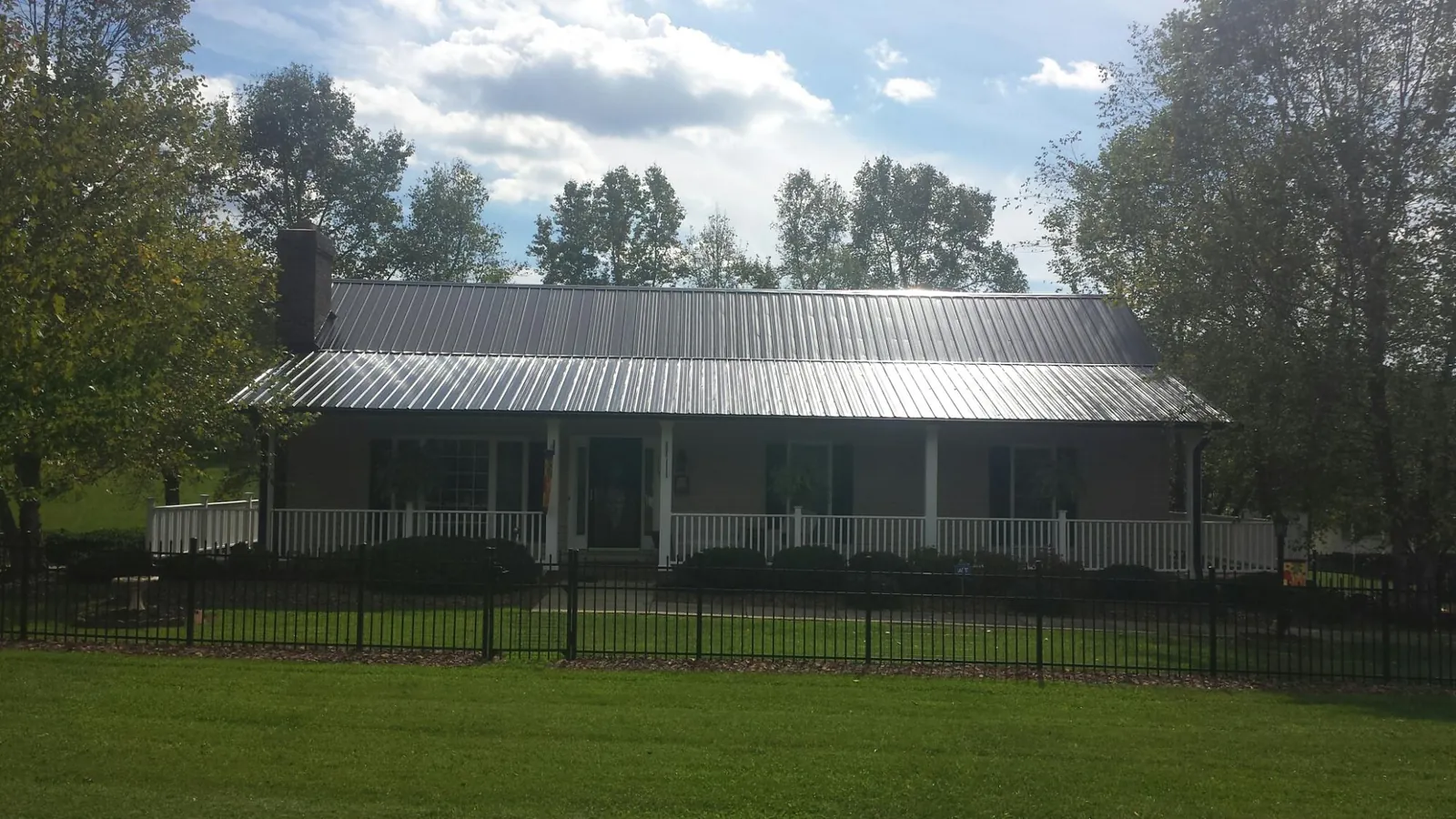 Gray metal roof on a brick ranch with a full width front porch — Gutter Guard Installation work by our crew in De Soto
