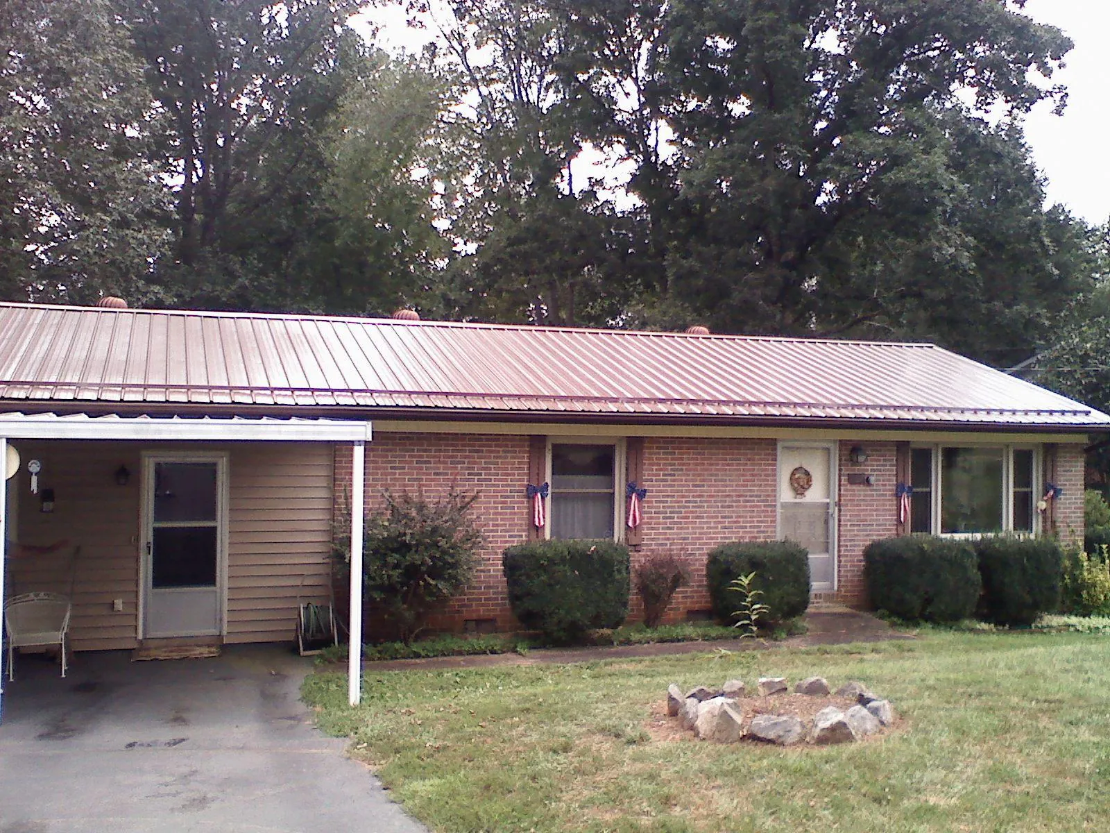 Bronze metal roof and carport on a brick ranch home — Roof Repair work by our crew in De Soto